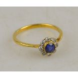 A circular cluster ring set with sapphire and diamonds in a white and yellow gold milgrain