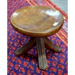 An African Yarouba carved wood stool having a dished circular seat raised on four outswept legs with