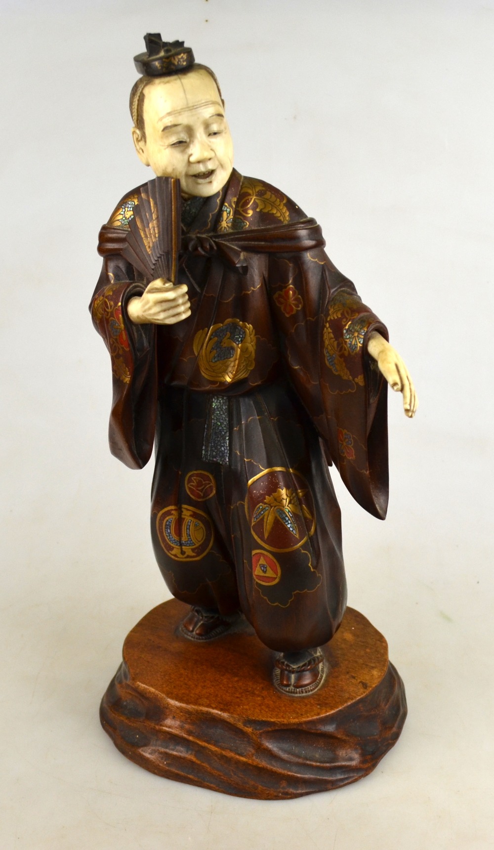 A Japanese carved wood standing figure of a man holding a fan, his robe gilt lacquered and inlaid