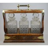 An Edwardian carved oak tantalus with plated mounts, containing three square cut glass decanters and