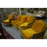 An Art Deco style walnut framed bergere suite comprising a three seat sofa, a pair of armchairs,