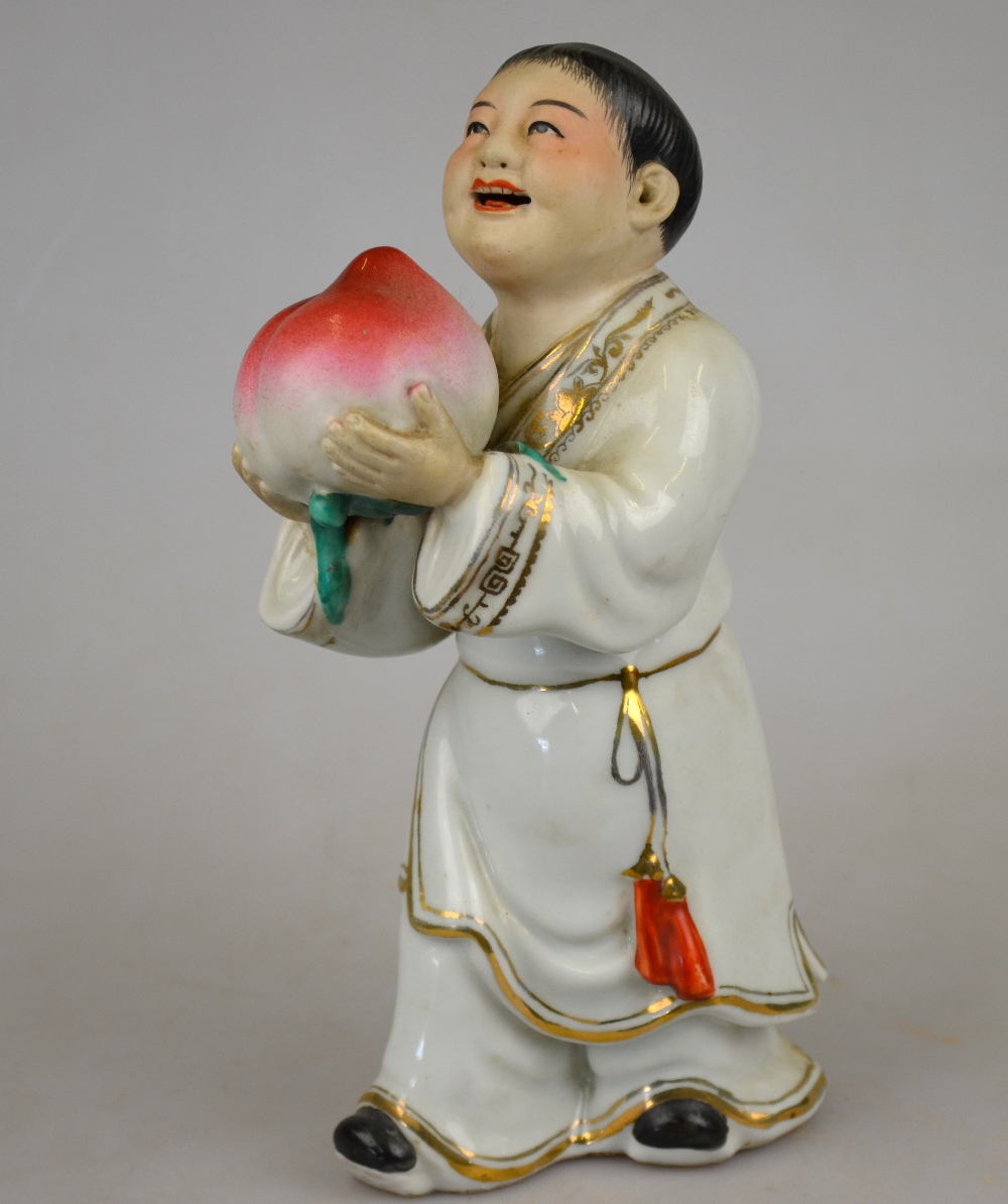 A Chinese porcelain famille rose figure of a man holding a giant peach, 20th century, 22 cm h.