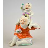 A Chinese porcelain famille rose figural group depicting a seated man with child on his shoulder,