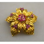 A retro style yellow metal chrysanthemum brooch with textured leaves having central set ruby
