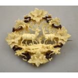 A Victorian carved ivory brooch pierced and in high relief featuring deer amongst fern and leaf