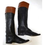 A pair of vintage soft black leather riding boots with tan leather cuffs