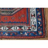 An antique Caucasian kazak style rug, the geometric pale design on red ground, 190 x 101 cm