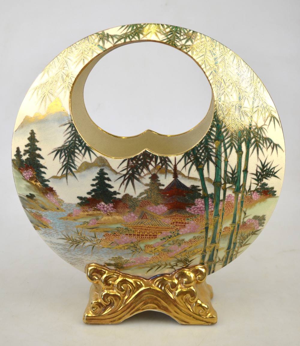 A Japanese Satsuma circular disk shaped vase raised on a gilt base decorated with pagodas in a