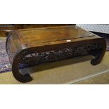 A Chinese hardwood low table with rounded ends, the end panels carved with prunus and having a