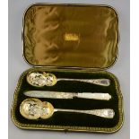 A late Victorian cased pair of silver and parcel gilt serving spoons with engraved decoration,