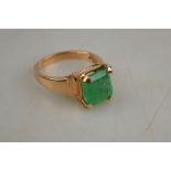 A single step cut green stone ring in four claw yellow metal setting