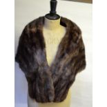 A dark brown musquash fur stole, a cream fur stole,