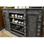 A late 19th century carved and stained oak breakfront open bookcase flanked by panelled and carved