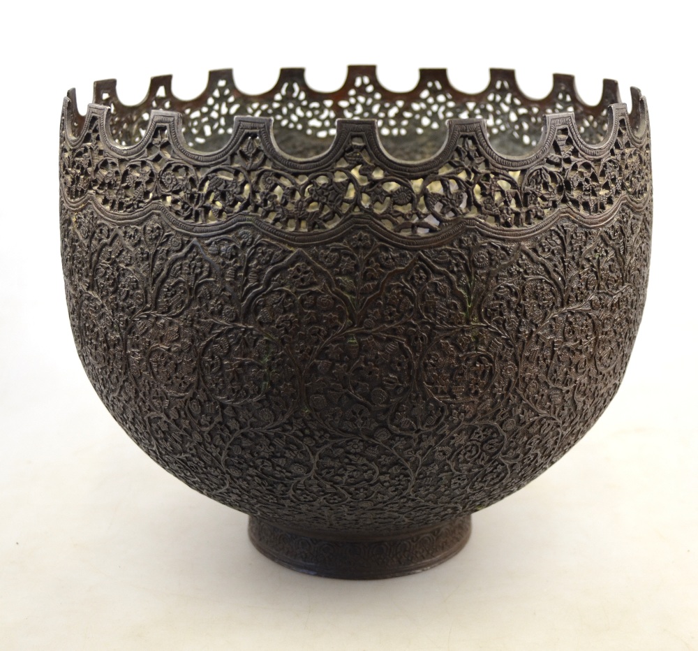 An antique Persian bowl cast overall with a foliate filigree pattern and having a crenulated