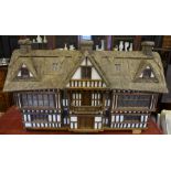 A large Robert Stubbs thatched dolls house of half-timbered design with central gable above a