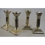 A late Victorian set of four loaded silver classical candlesticks on stepped square bases,