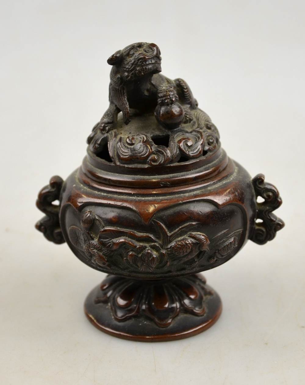 A Japanese bronze incense burner decorated in relief with panels of birds, the reticulated cover