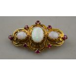 A 9ct yellow gold triple scroll style brooch set with three white opals and eight small rubies