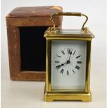 A French brass carriage timepiece with bevelled glass panels and enamel dial,