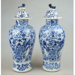 A pair of Chinese blue and white baluster vases and covers decorated with figures carrying a floor
