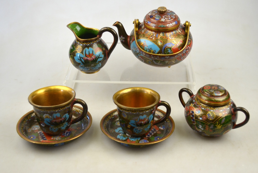 A Japanese cloisonne tea set for two decorated with shaped panels of water lilies and wisteria,
