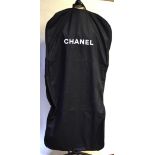 A full length black garment/suit carrier with 'CHANEL' in white lettering