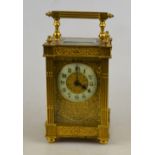 An ornate gilt brass carriage timepiece with reeded square pillars and decorative gilt dial with