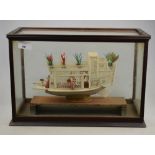 Chinese bone model of a houseboat with figures and foliage in glazed case