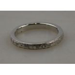A hinged platinum wedding ring engraved with flower motifs and having millgrain edge,