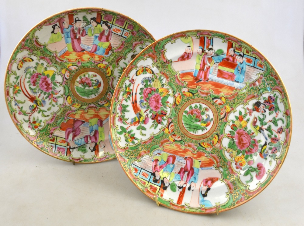 A pair of Chinese Canton famille rose plates decorated with alternating panels of figures on a