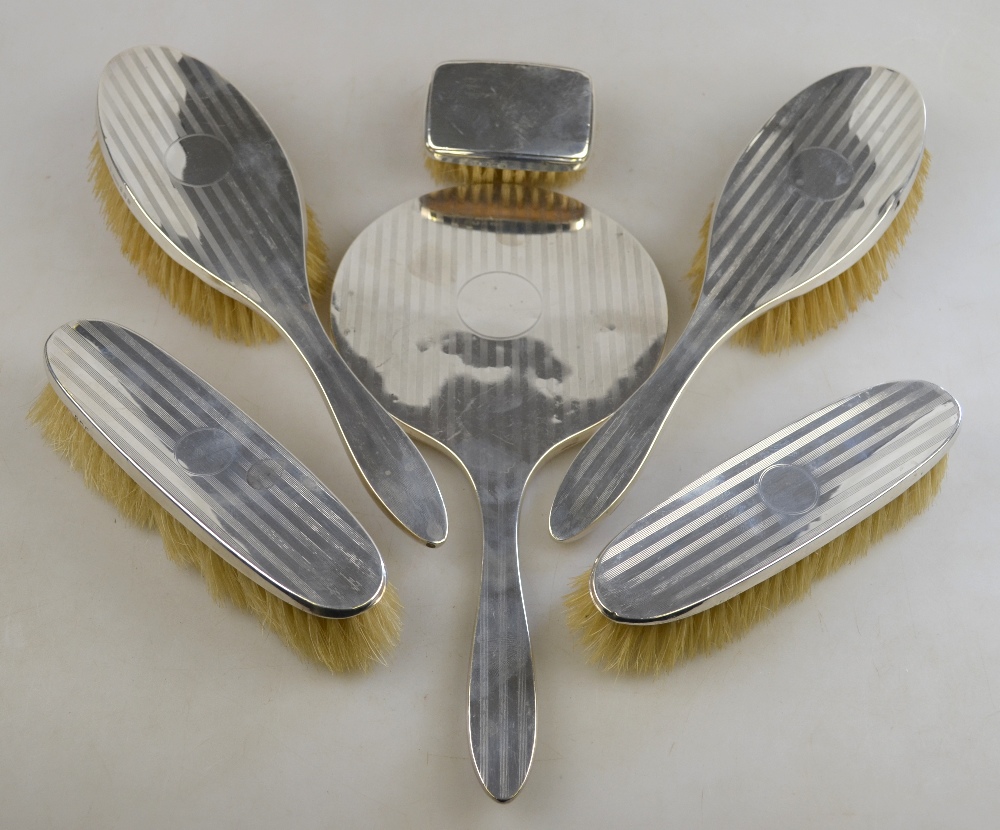 An engine-turned silver five-piece brush set, Birmingham 1922, to/w a small silver-backed brush,