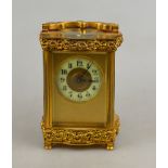 A gilt brass carriage timepiece with decorative top and bottom friezes, gilt dial with ivorine