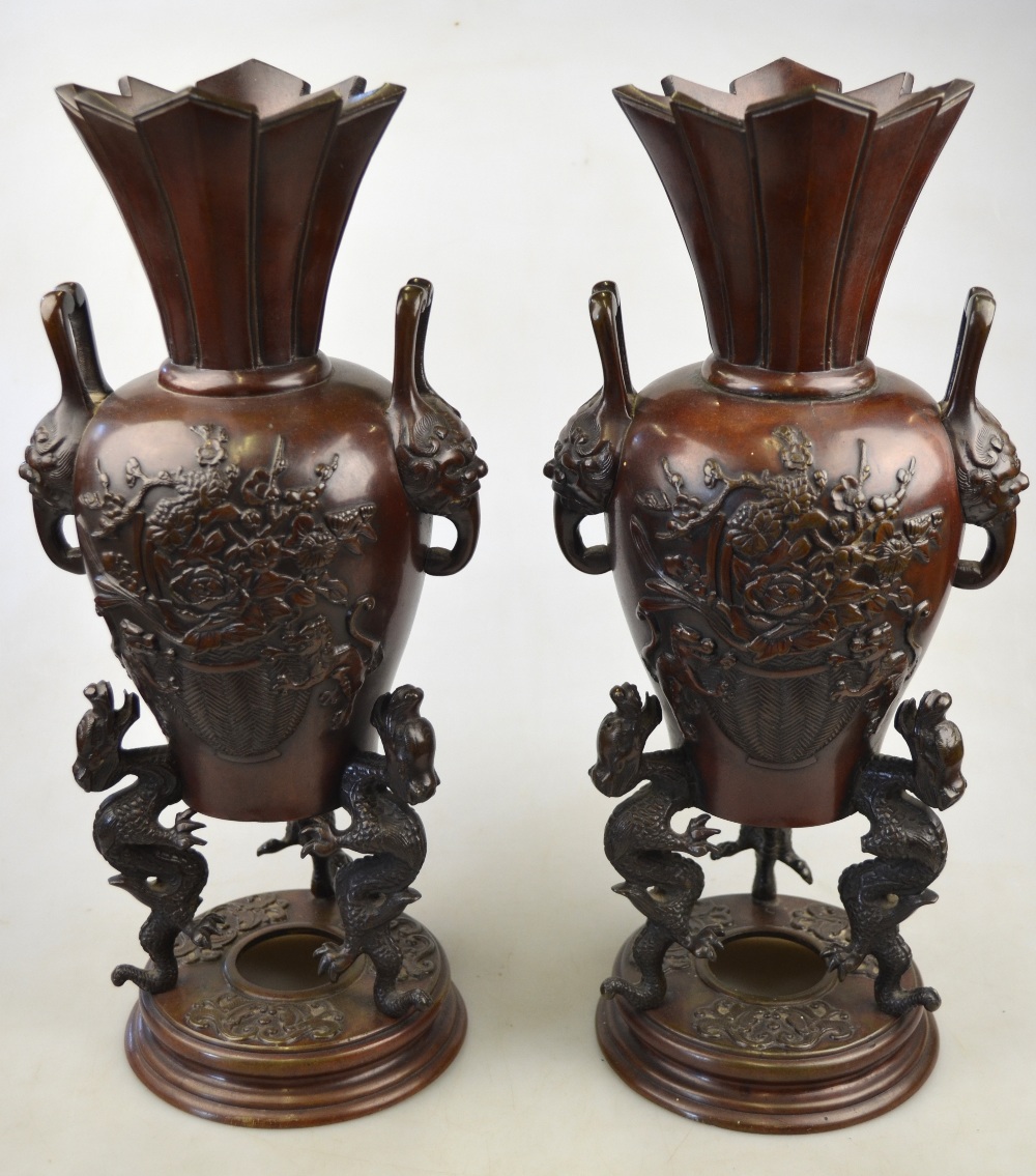 A pair of Chinese bronze vases each cast with a vase of flowers, twin mask handles, supported by