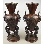 A pair of Chinese bronze vases each cast with a vase of flowers, twin mask handles, supported by