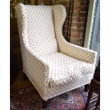 An antique wing back armchair traditionally re-upholstered in leaf pattern material