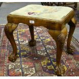 A George III walnut stool having an embroidered covered seat pad, raised on four hip shell carved