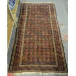 An antique Belouch rug, the repeating design on red/brown ground, 192 x 99 cm Condition Report