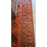 A large antique Afghan carpet, the rust field with four rows of geometric guls within multi-borders,