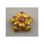 A retro style yellow metal chrysanthemum brooch with textured leaves having central set ruby