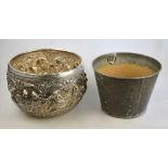 An Asian heavy white metal cache-pot profusely embossed with figures and buildings within floral