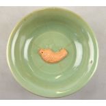 Chinese early Ming Dynasty - a Longquan celadon saucer, the interior decorated with a fish left in