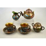 A Japanese cloisonne tea set for two decorated with shaped panels of water lilies and wisteria,
