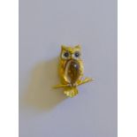 An 18ct yellow and white gold brooch featuring a textured owl on branch, set with cabochon citrine