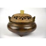 A Chinese bronze shallow globular censer with two loop handles standing on three short feet,