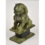 A Chinese green hardstone carving of a dog of Fo seated on a rectangular plinth, 18.5 cm h.