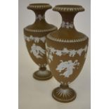 A pair of brown jasper ware baluster vases decorated with an angel and baby beneath a band of