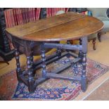 A late 17th century oak gateleg table having wide plank drop leaves to form an oval top,