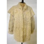 A 1980's cream shearling lamb fur jerkin/jacket with stitched cream leather sleeves, 52 cm across