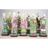 A set of porcelain famille rose figures of the eight Daoist immortals and Shoulau, c/w hardwood