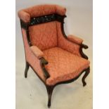 A late 19th century carved mahogany framed wing back salon armchair in pink upholstery raised on